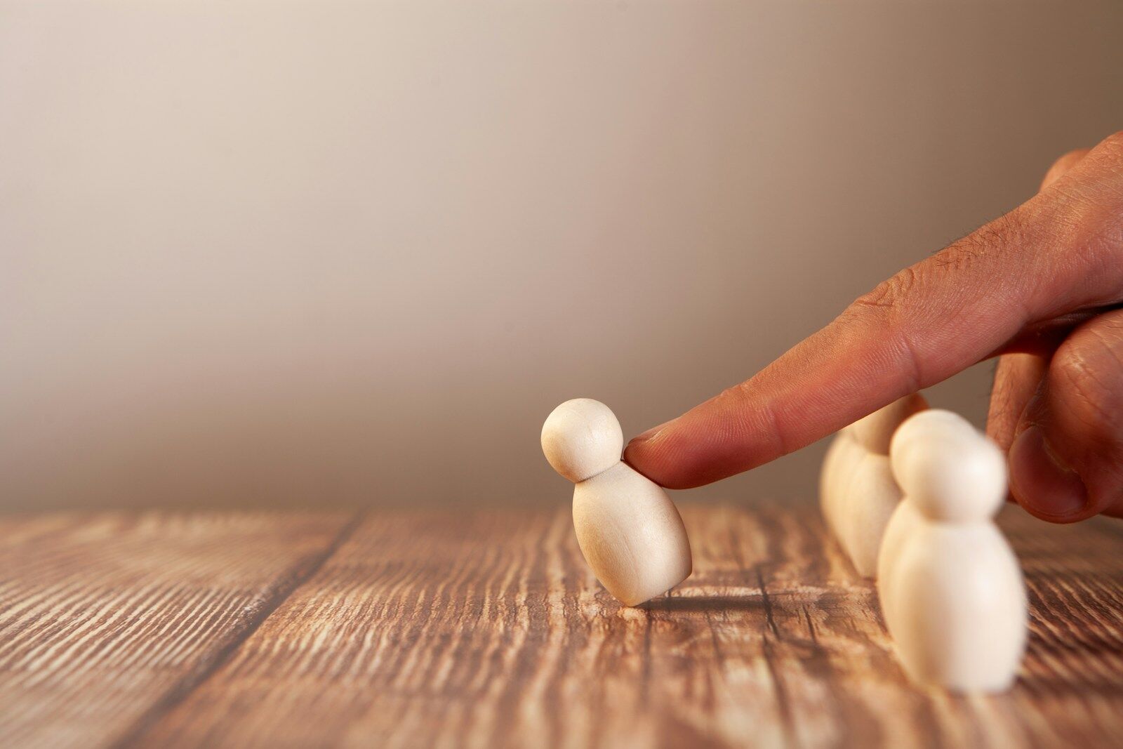 Finger pushing a small wooden figure over a group